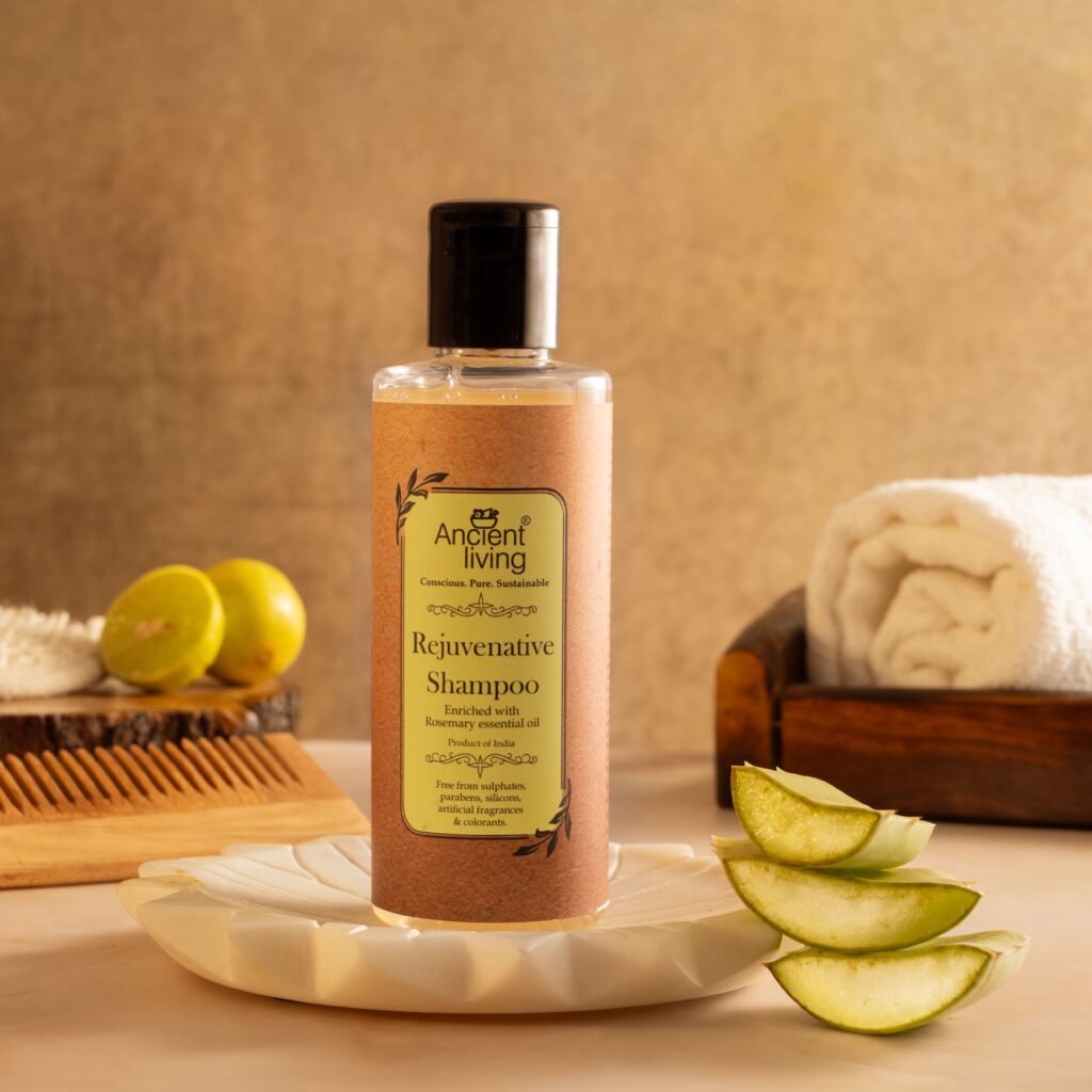 product photograph of a shampoo bottle on a circular wood slice, styled with cut limes, aloe vera stalks, and neutral textures to create an organic, premium aesthetic.