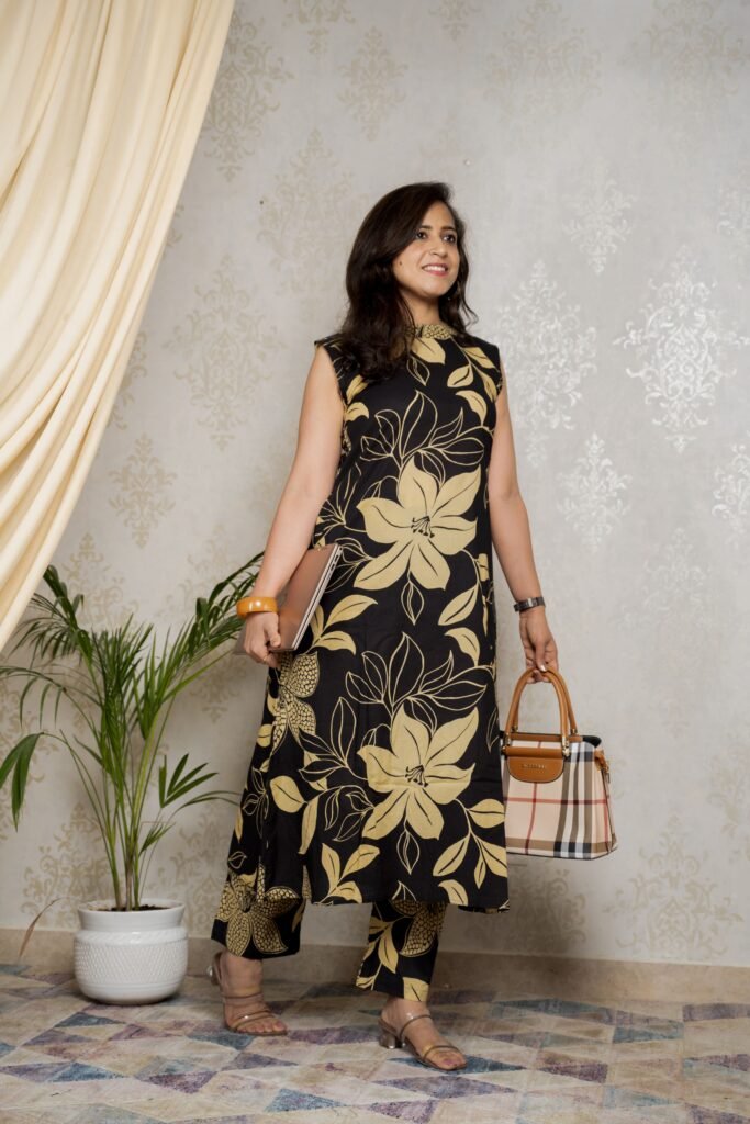 A woman poses gracefully in a handcrafted embroidered suit set, standing against a neutral backdrop that highlights her elegant poise.